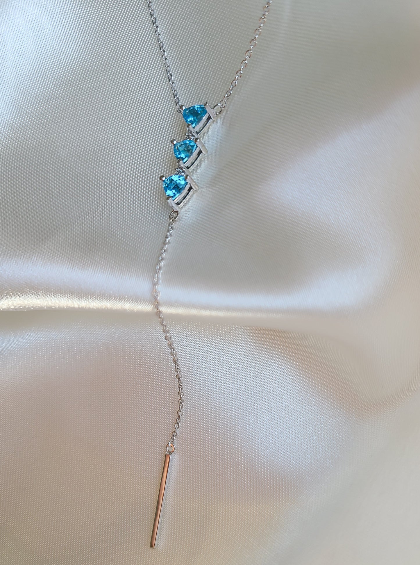 Falling necklace with three vivid blue trilliant topaz and natural diamonds